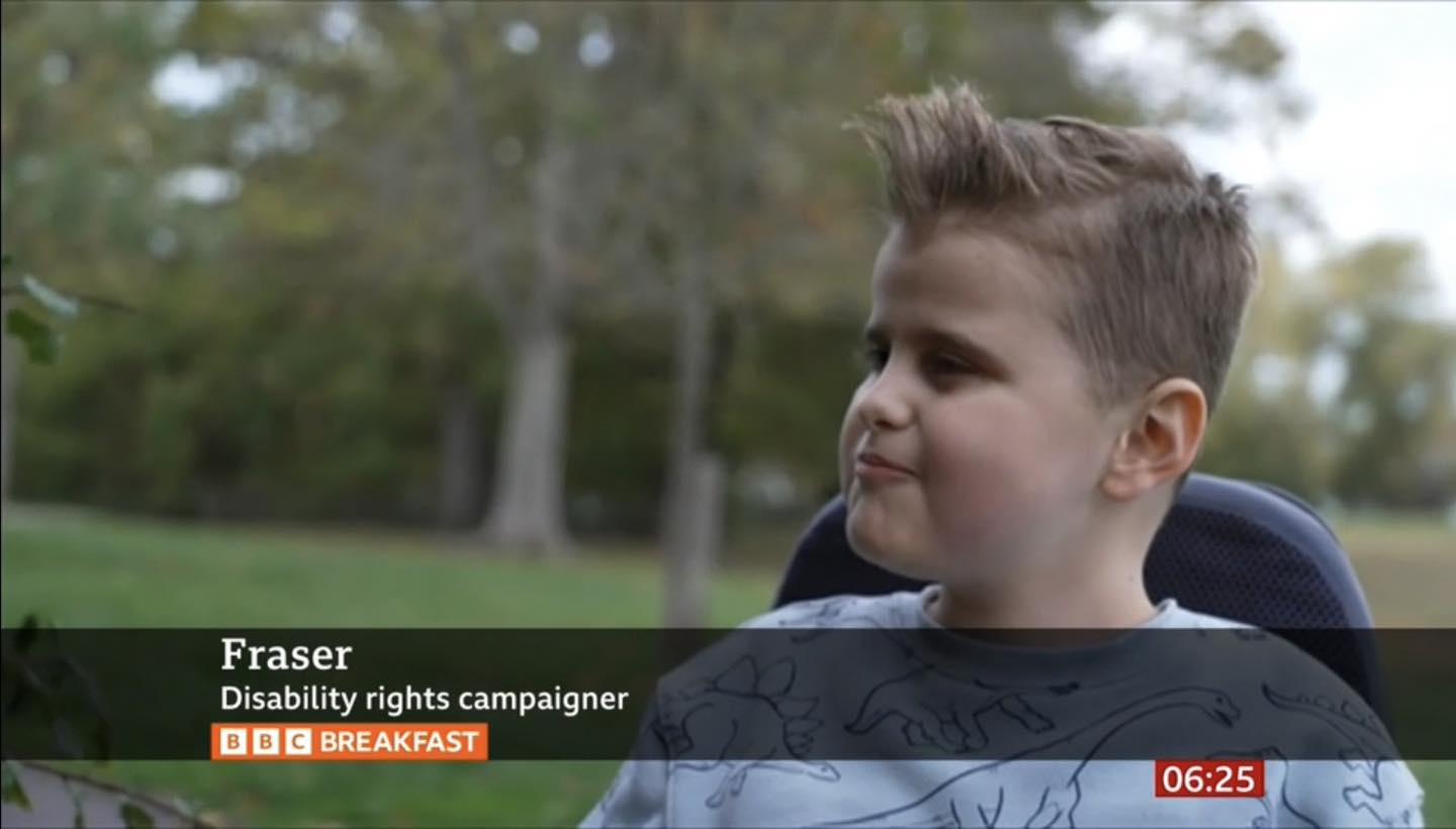 Image shows a screen shot of 10 year old Fraser when he featured on BBC News. He is talking to the interviewer. The caption on the photo says 'Fraser - disability rights campaigner'.