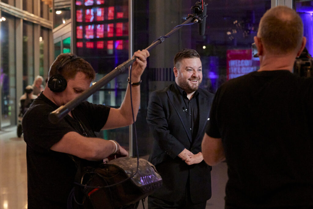 Alex Brooker stood laughing in a candid shot