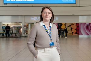 A dark blonde haired woman stood in an airport terminal.