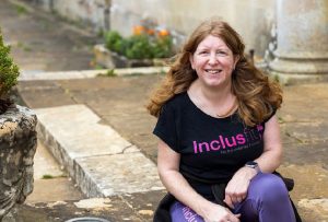 Sam, a strawberry hair lady, dressed in a black inclusfit top and purple leggings, sat outside Lydiard House, Swindon